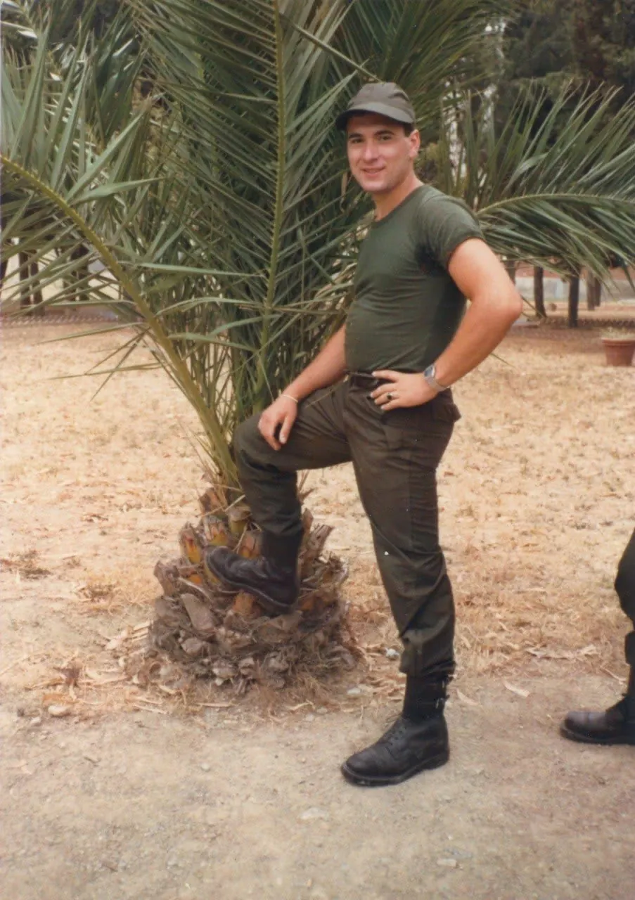 Fotografia d'epoca: giovane in divisa militare verde sotto una palma